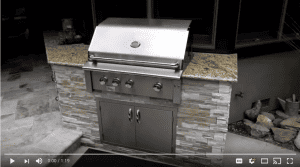 Barbecue island with gas grill, granite countertop, and stacked stone