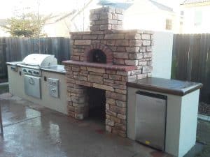 outdoor kitchen with a stone fireplace and pizza oven